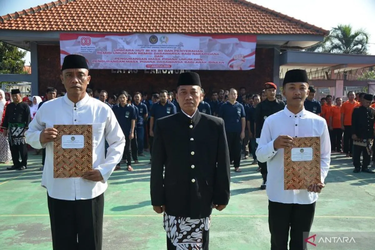 Kepala Lembaga Pemasyarakatan (Lapas) Kelas IIB Lamongan Heri Sulistyo (tengah) berfoto bersama usai menyerahkan surat keputusan remisi secara simbolis kepada salah dua warga binaan yang mendapat remisi dalam peringatan HUT ke-80 Kemerdekaan RI di Lamongan, Jawa Timur, Minggu (17/8/2025). (Alimun Khakim)